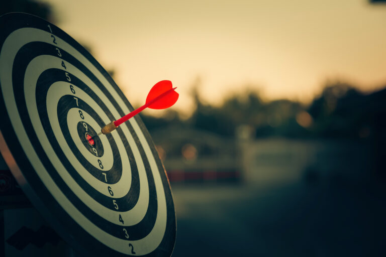 bullseye target or dart board has red dart arrow throw hitting t